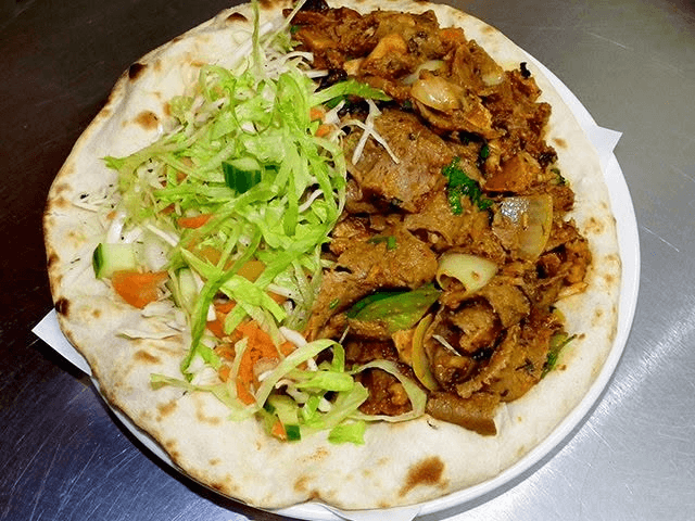 Flatbread topped with seasoned meat, onions, peppers and fresh salad